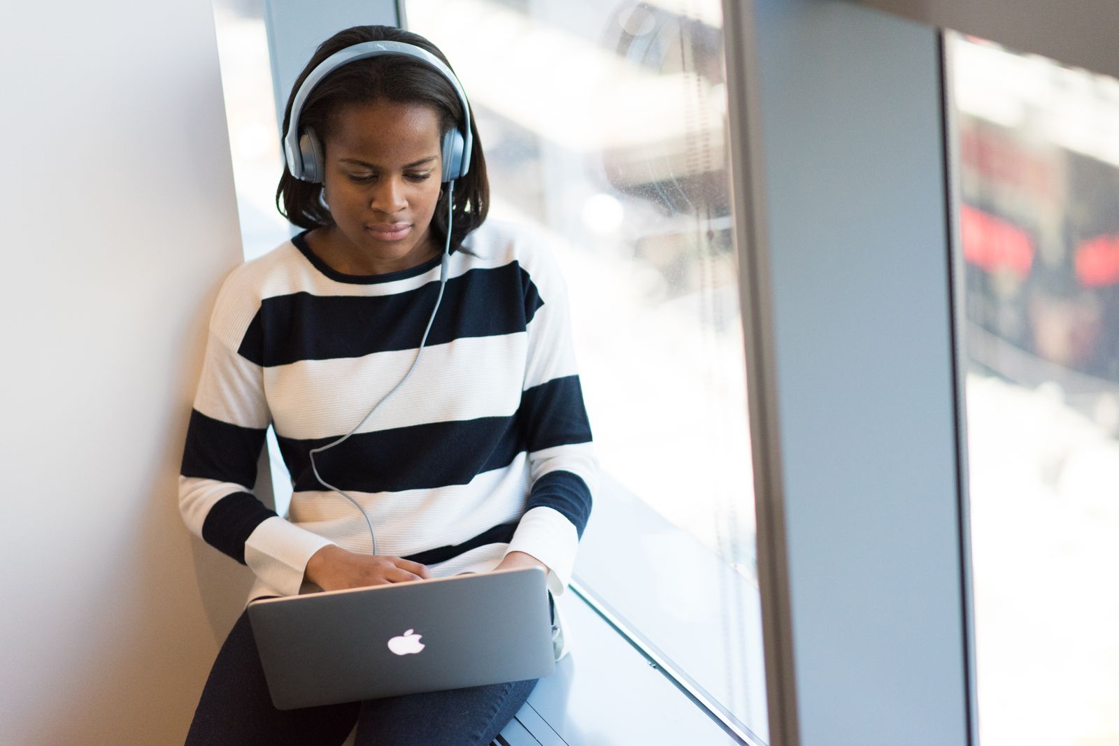Studying on a laptop with headphones by a bright window