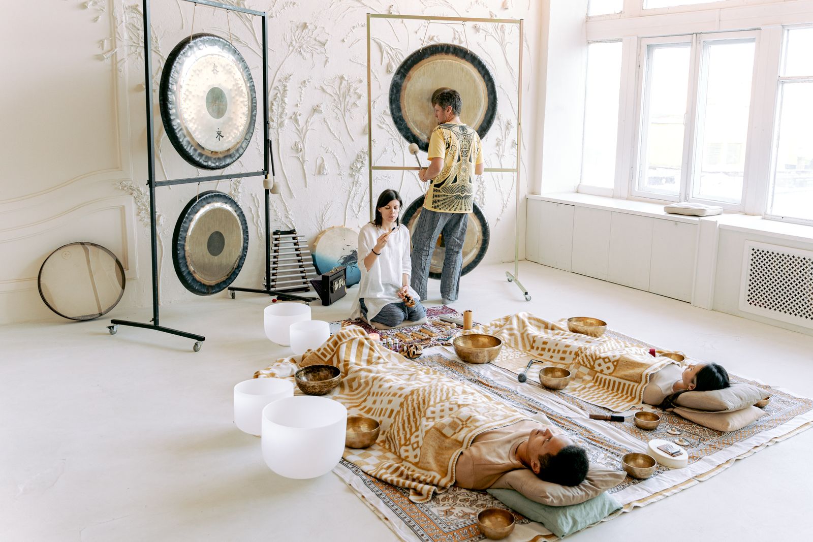 A group sound bath session with gongs and singing bowls in a bright studio