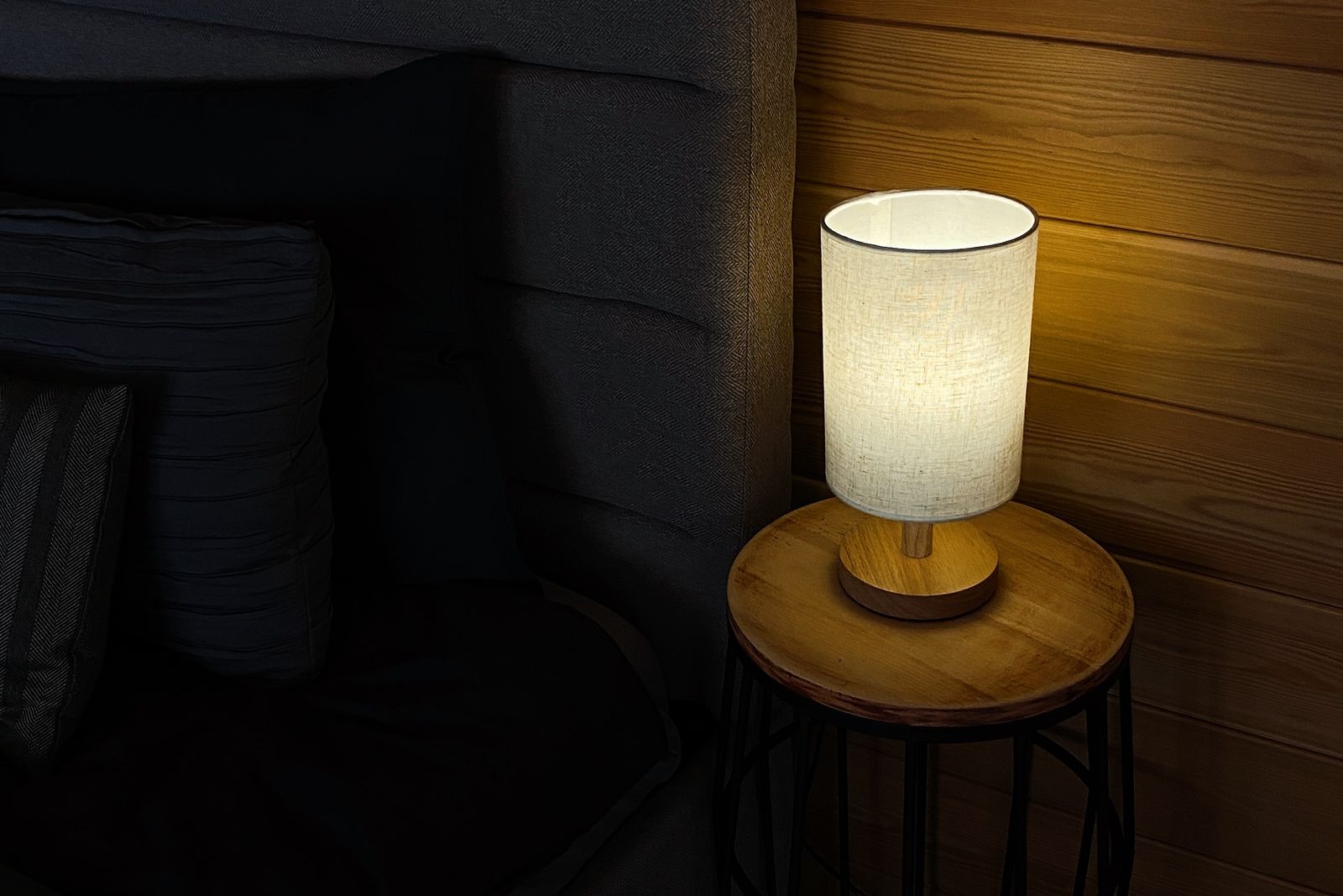 A warm bedside lamp glowing softly in a dark bedroom