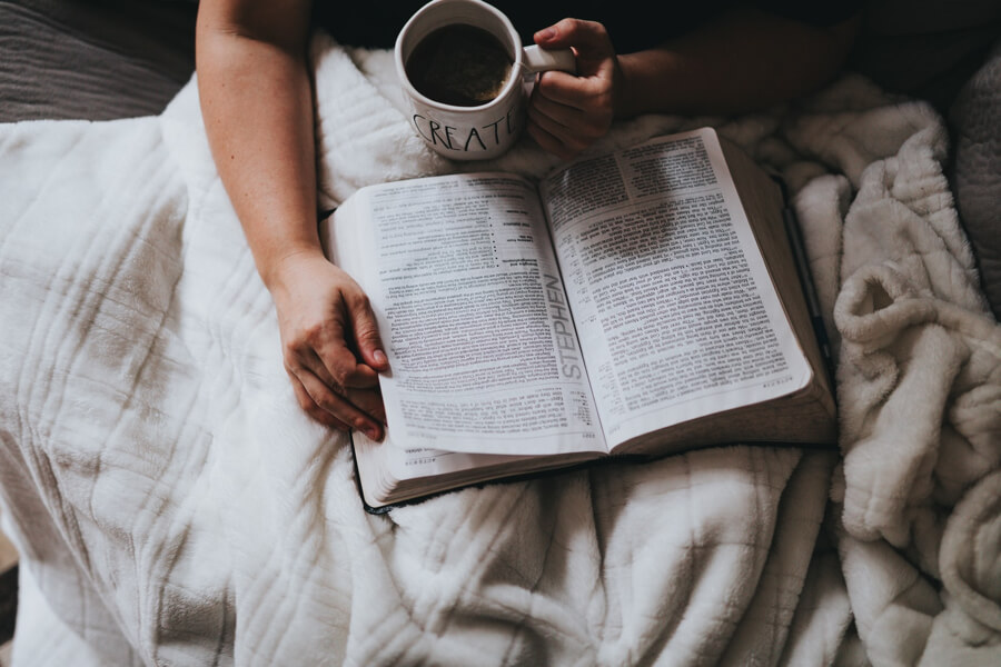 with book and cup in the bed